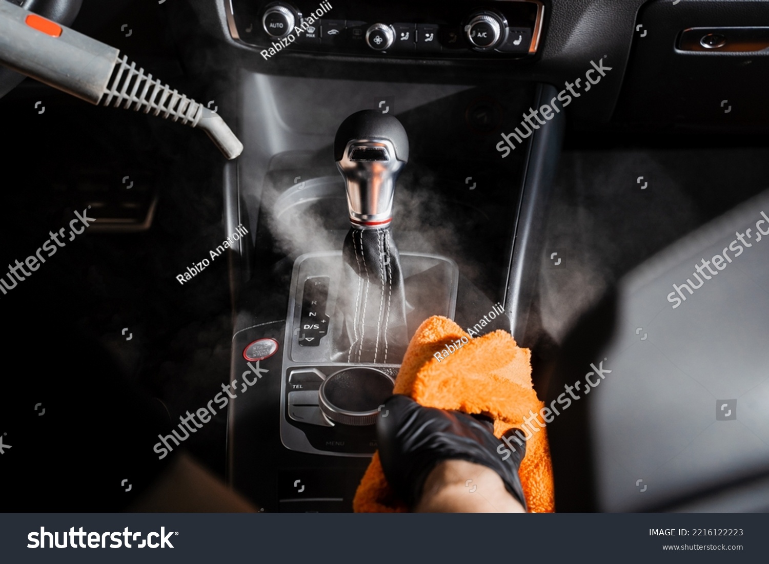 Steam cleaning of gearbox and dashboard in car. Vaping steam. Cleaning individual elements of black leather interior in auto. Creative advert for auto detailing service #2216122223