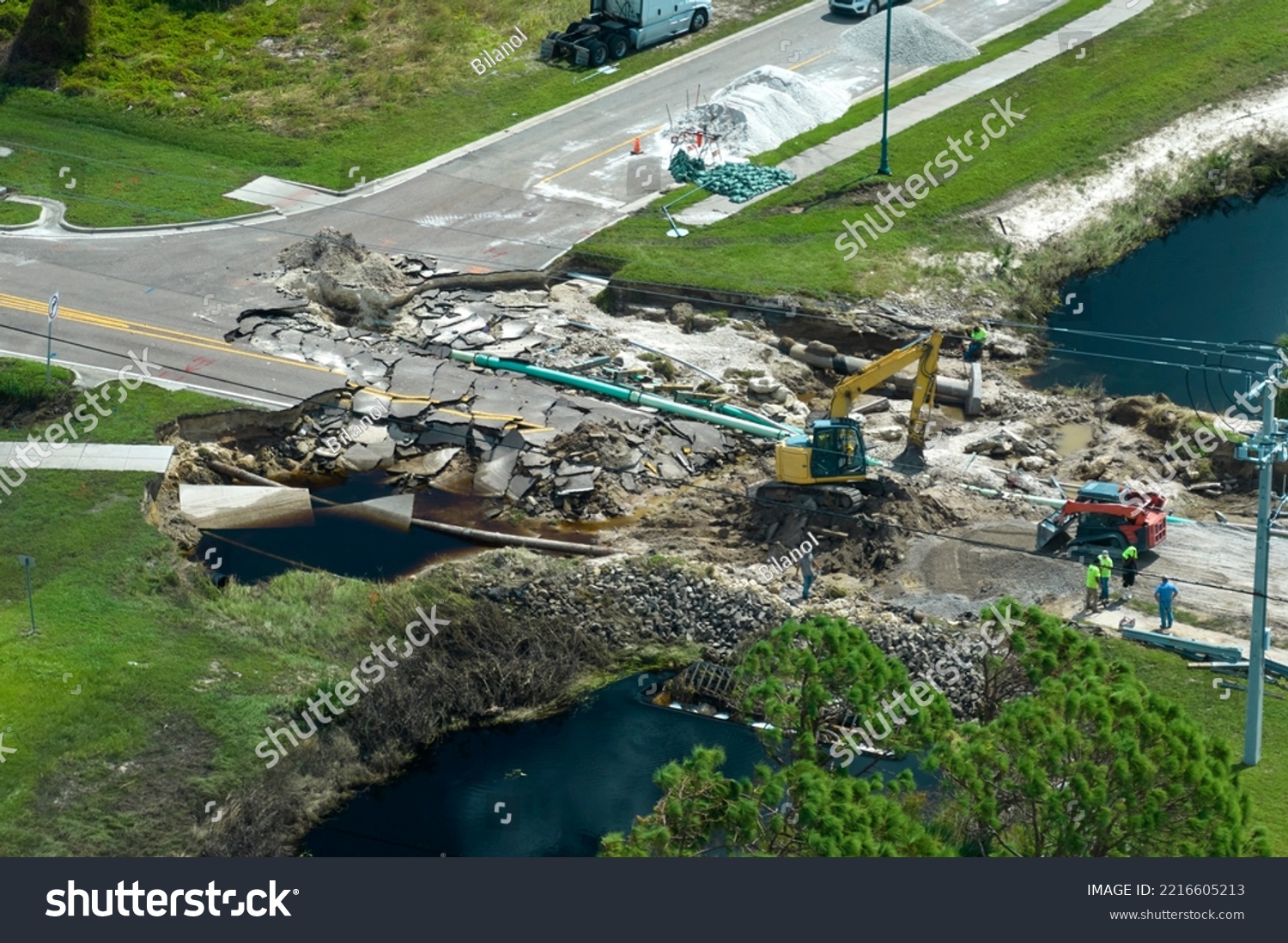 Aerial view of reconstruction of damaged road bridge destroyed by river after flood water washed away asphalt. Rebuilding of ruined transportation infrastructure #2216605213