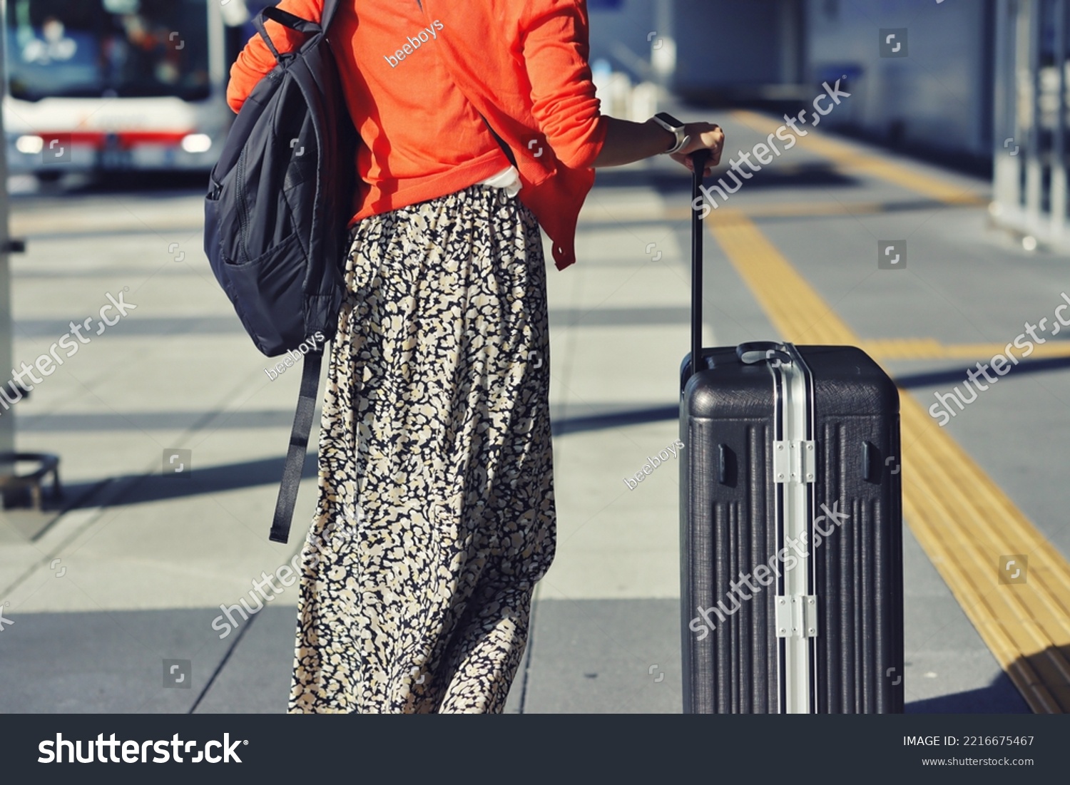 Back view of a woman traveling with luggage #2216675467