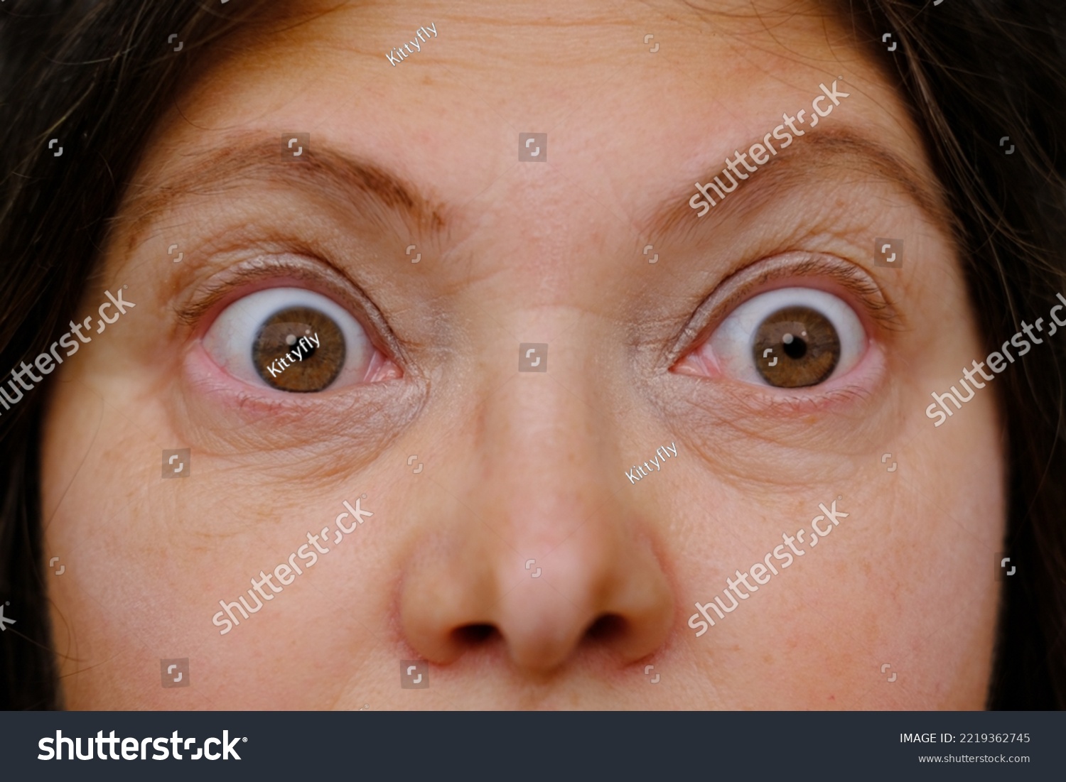 middle-aged mature woman with bulging eyes, upper face close-up, goggle eyes in fright, staring at camera, Very strong surprise or fright, horror in look, concept of cosmetic anti-aging procedures #2219362745