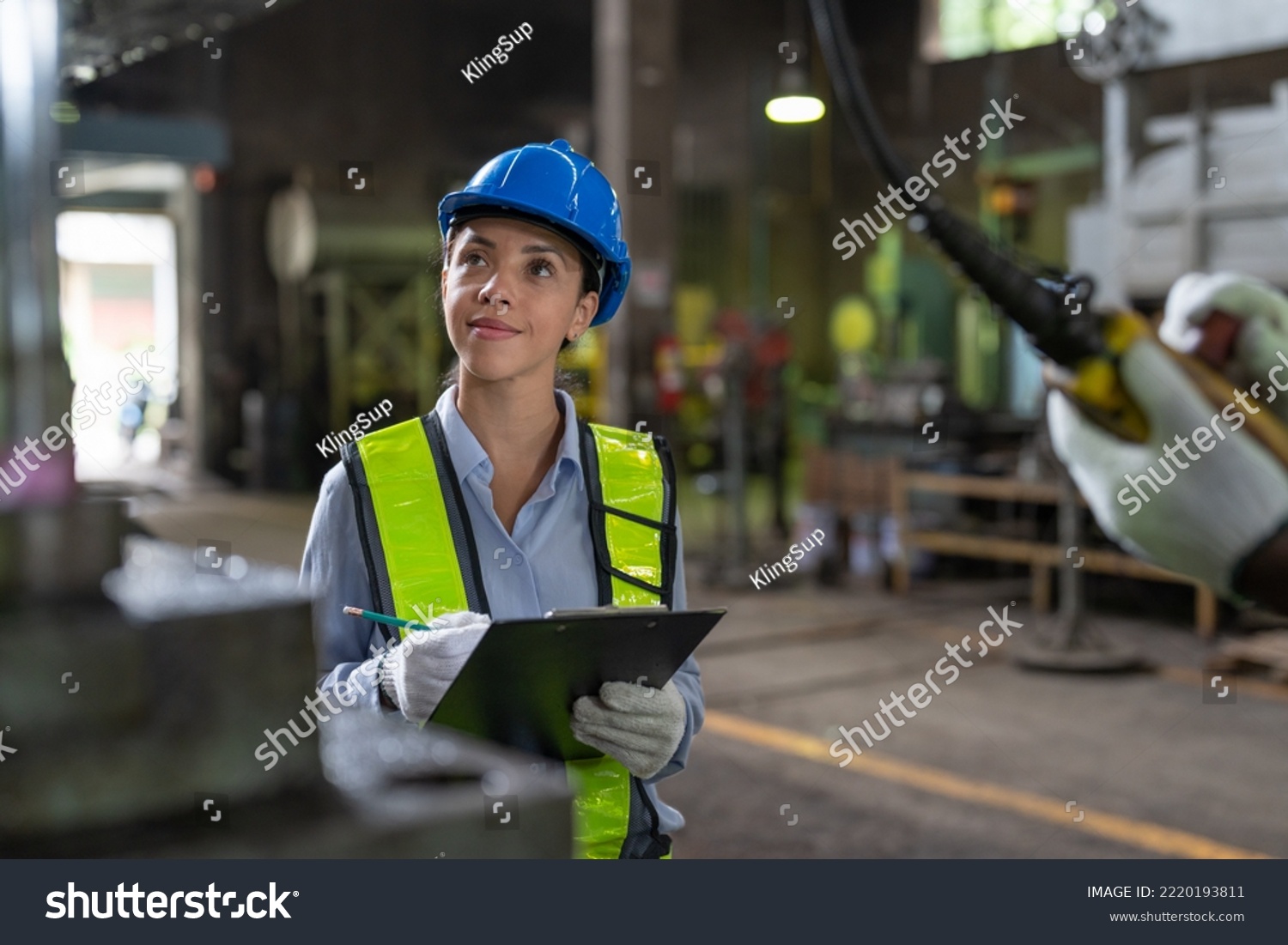 Female engineer in vest and helmet safety with clipboard checking and repairing machine at heavy metal factory.Preventive Maintenance concept #2220193811