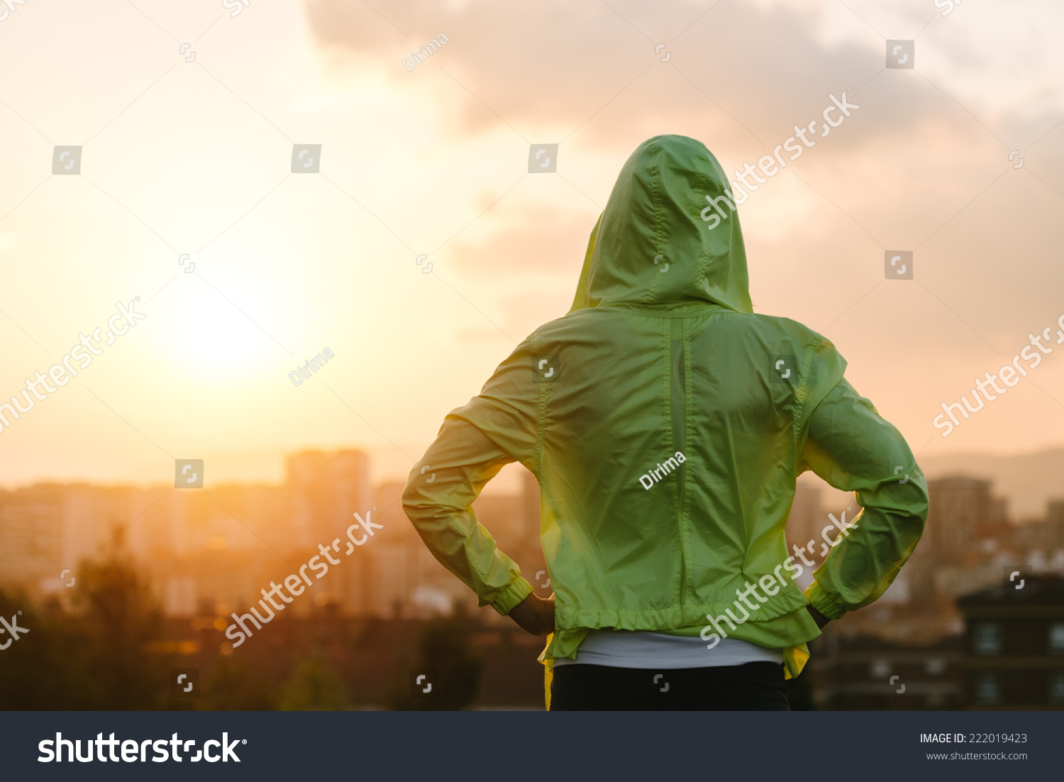 Back view of athlete looking sunset over city skyline after exercising. Motivation, sport and fitness lifestyle concept. #222019423