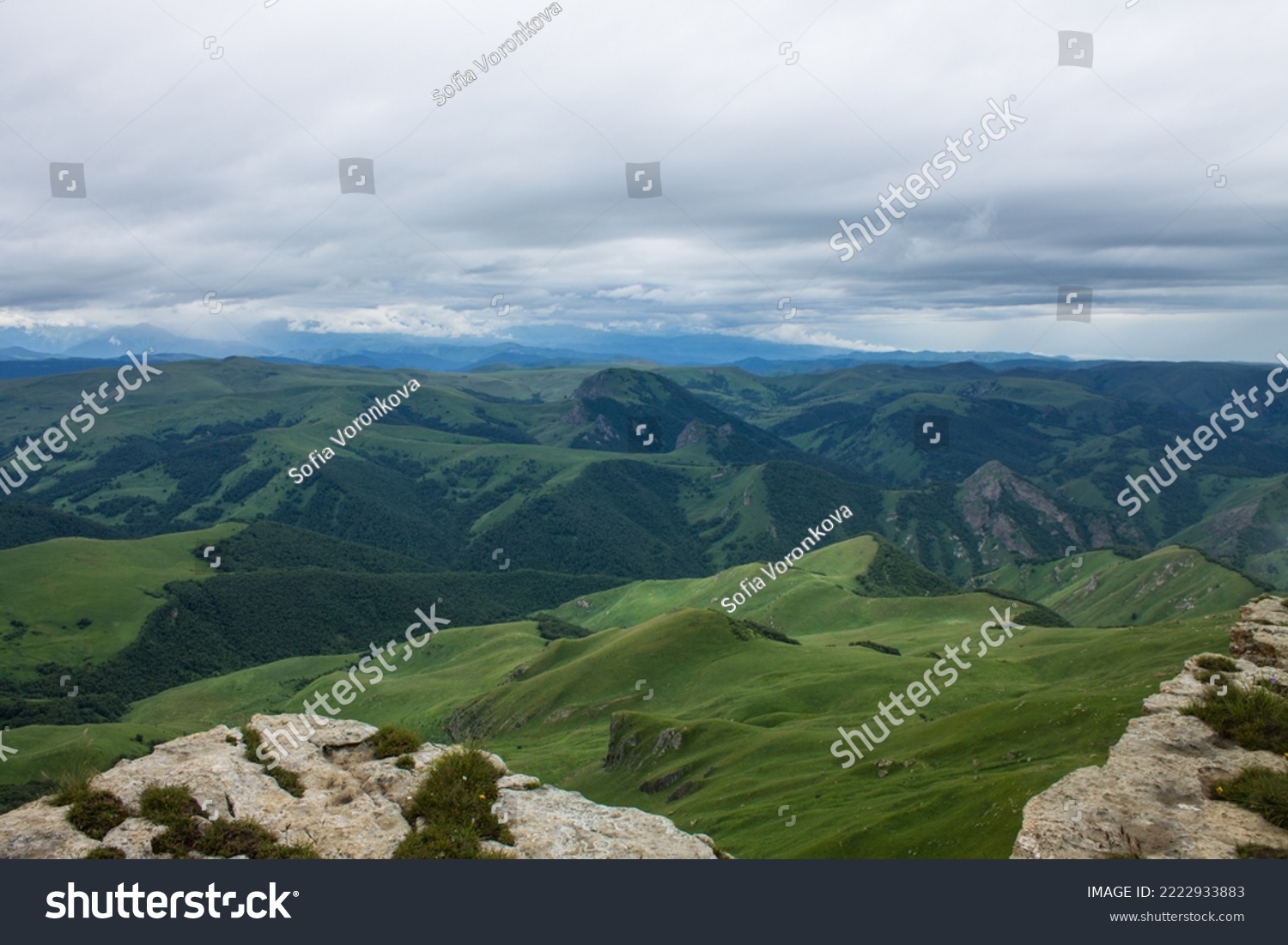 Panoramic view of green mountains and hills from the Bermamyt plateau in Karachay-Cherkessia in Russia on a cloudy summer day and copy space in a hazy haze on the horizon #2222933883