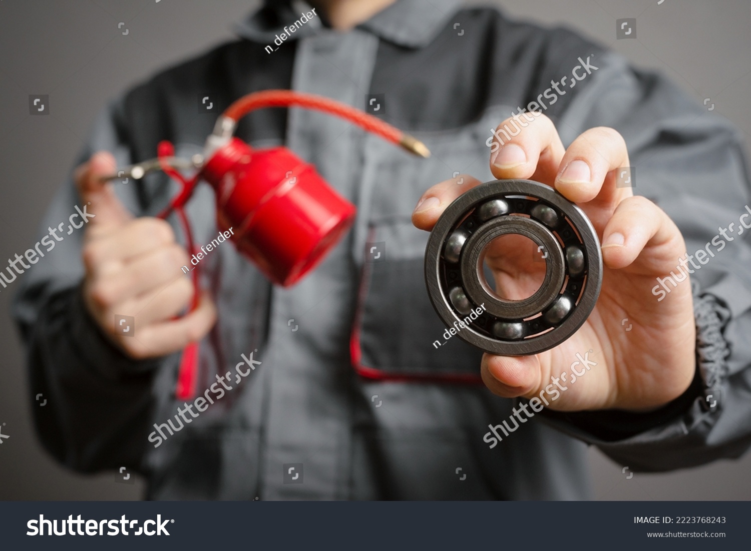 Car service worker holding in hands a red oil can and car parts on dark background closeup. #2223768243