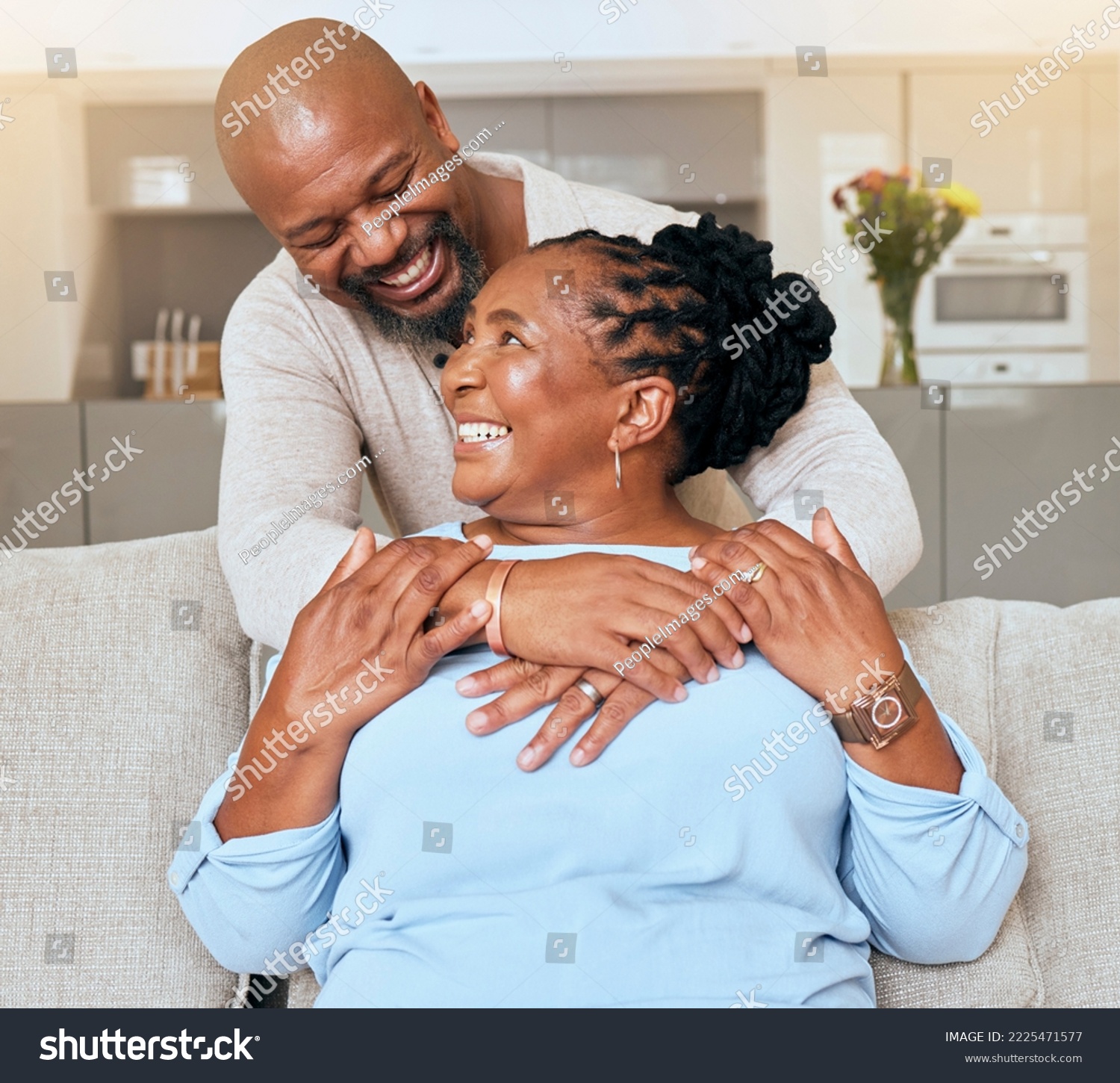 Senior black couple, hug and sofa with smile, love or happiness in home, living room or relax together. Elderly happy couple, African and embrace by couch, lounge care, romance or bonding #2225471577