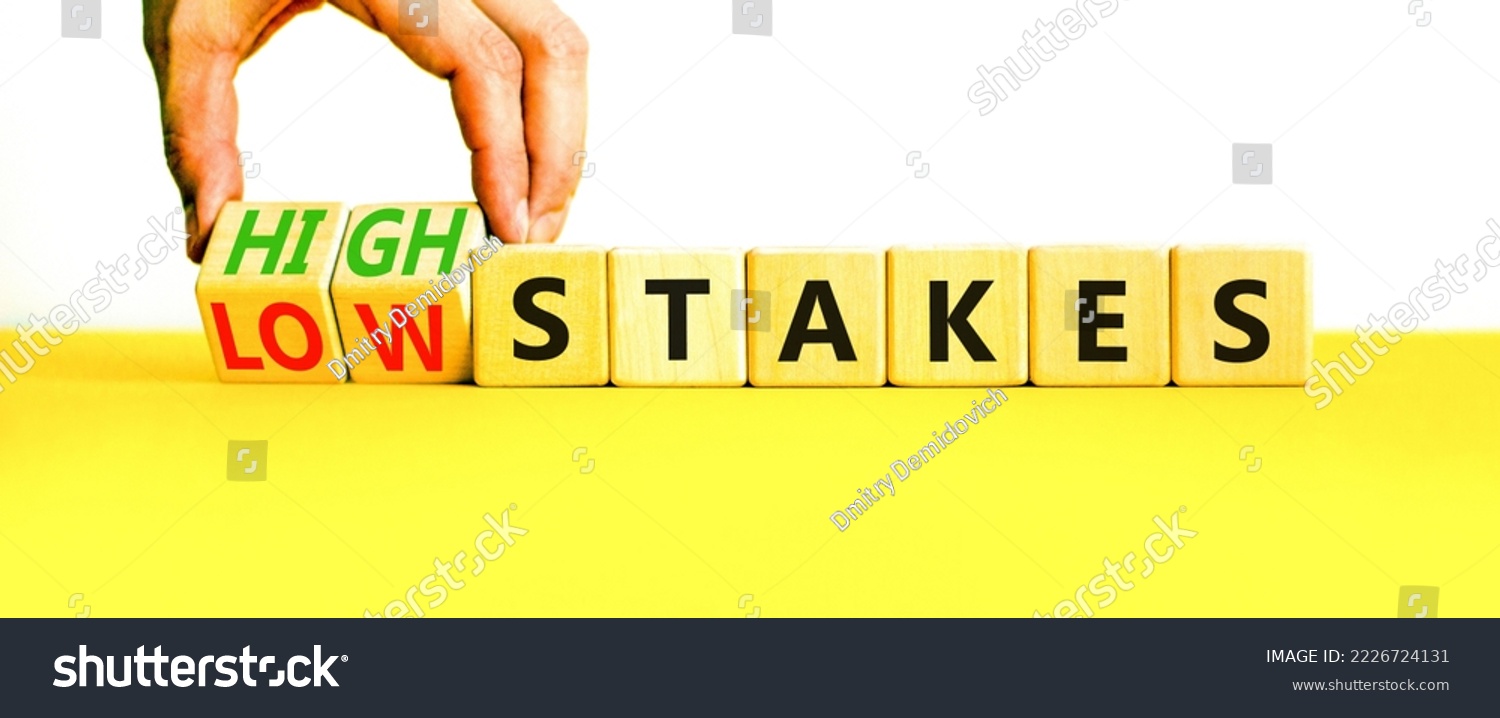 High or low stakes symbol. Concept words High stakes and Low stakes on wooden cubes. Businessman hand. Beautiful yellow table white background. Business high or low stakes concept. Copy space. #2226724131