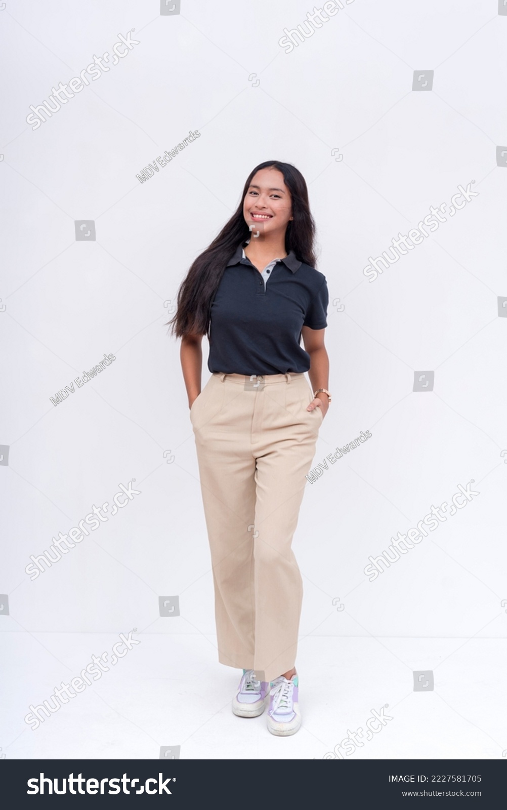 A lovely Filipina intern in a black polo shirt and khaki pants. Isolated on a white background, full body photo. #2227581705