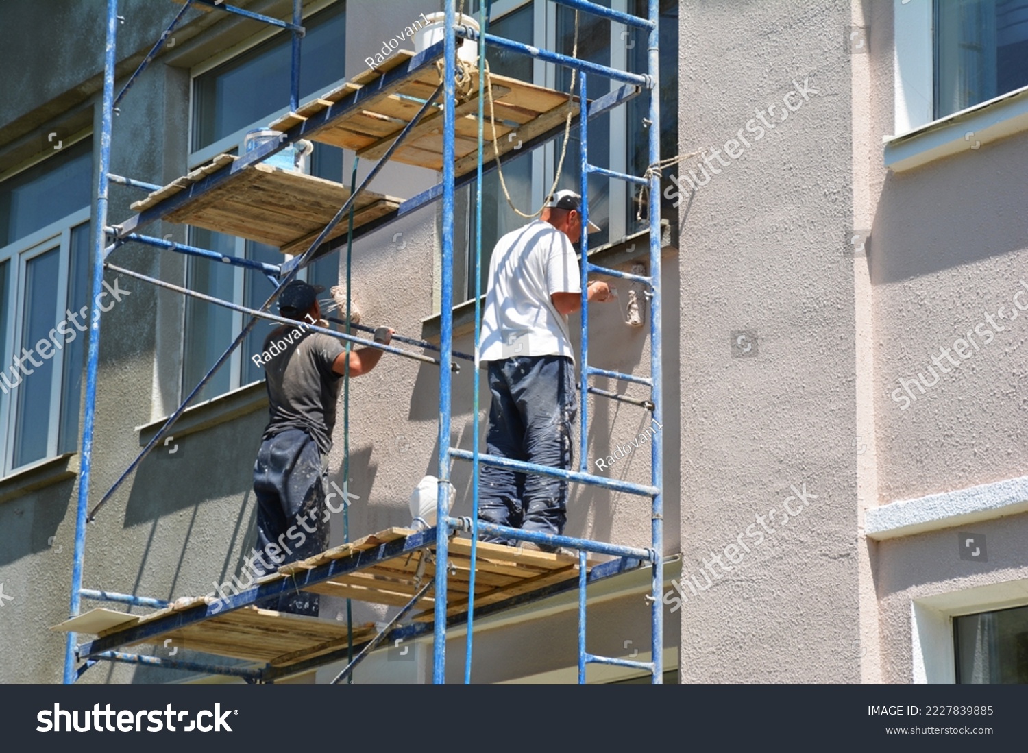 Builder contractors painting external walls outside house facade. Close up on painting house outside wall. #2227839885