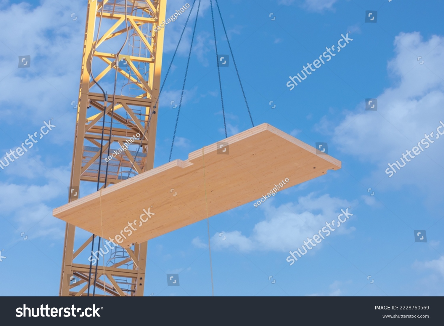 A complete laminated floor panel of a mass timber multi story green, sustainable, residential high rise apartment or office building construction project being lowered into place by a crane #2228760569