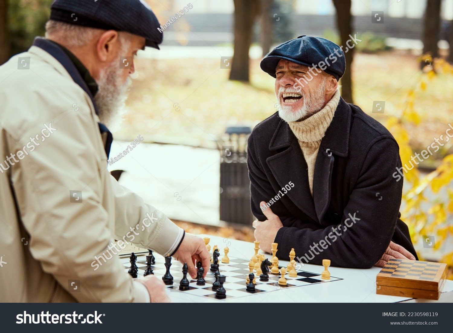 Portrait of two senior men playing chess in the park on a daytime in fall. Happy and delightful. Concept of leisure activity, friendship, sport, autumn season, game, entertainment, old generation #2230598119