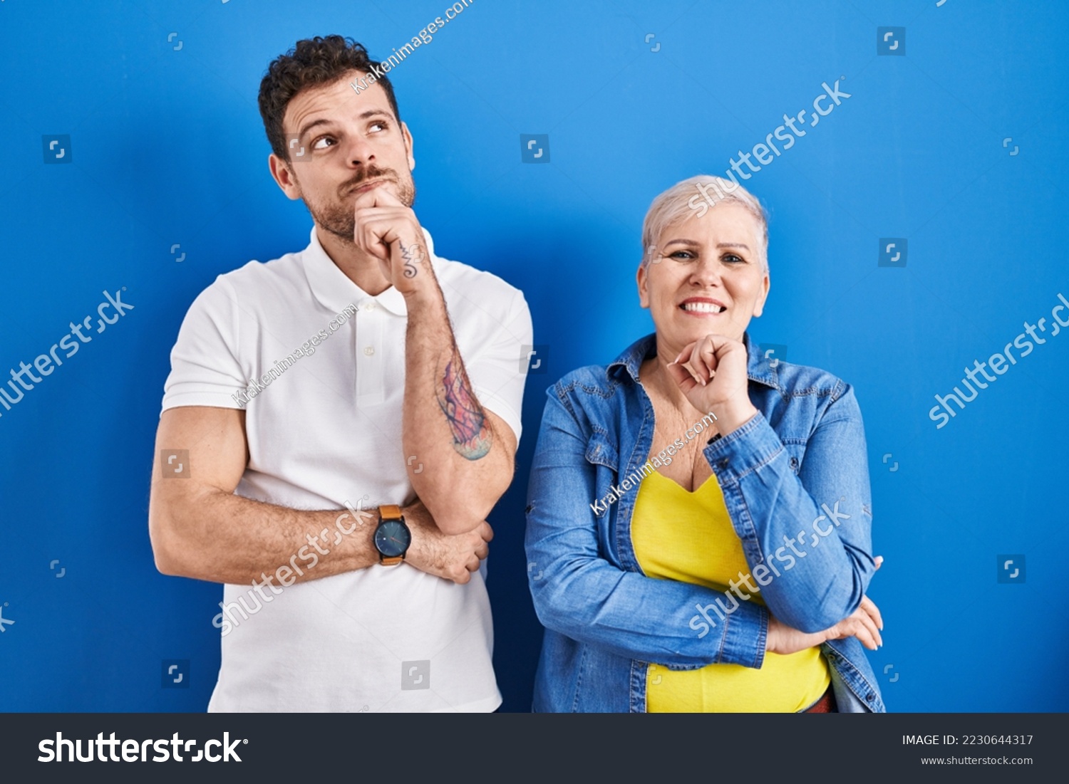 Young brazilian mother and son standing over blue background with hand on chin thinking about question, pensive expression. smiling and thoughtful face. doubt concept.  #2230644317