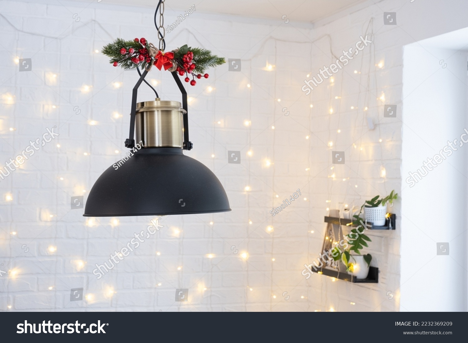 The black lampshade in the industrial loft style is decorated with spruce branches for Christmas and New Year on the background of fairy lights garlands. Close-up, minimalism #2232369209