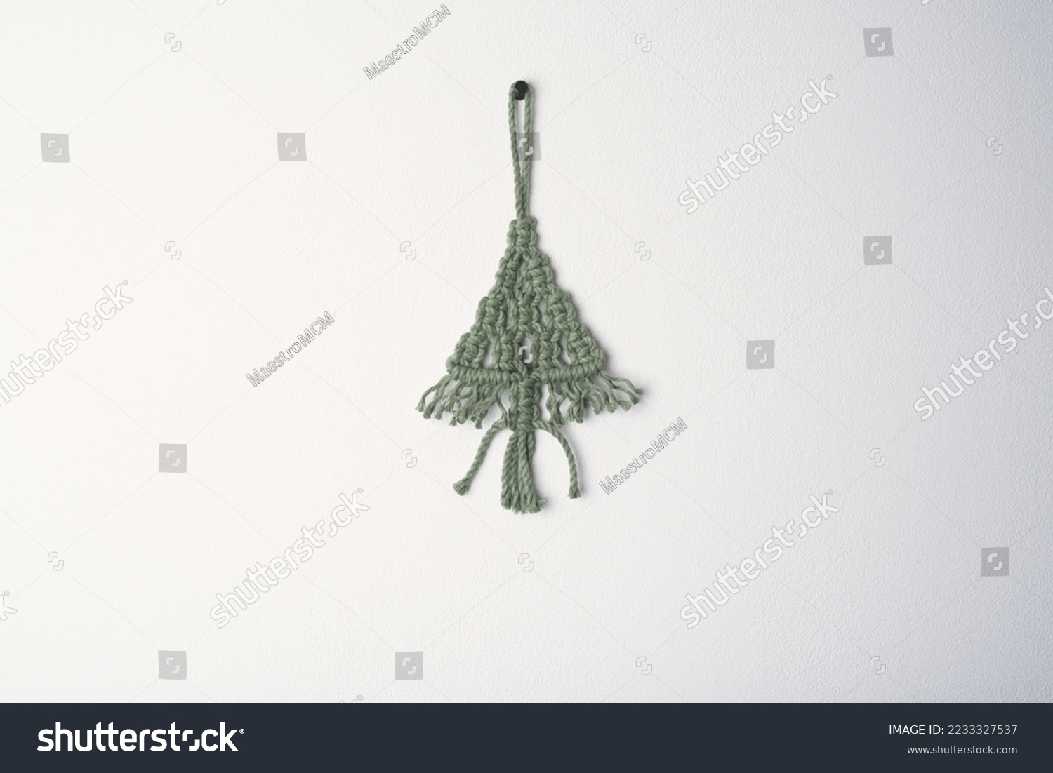 Christmas handmade macrame tree ornament winter holiday, green eco macramé Christmas tree decorations in boho style hanging. tree made from cotton green string on white wall background  #2233327537