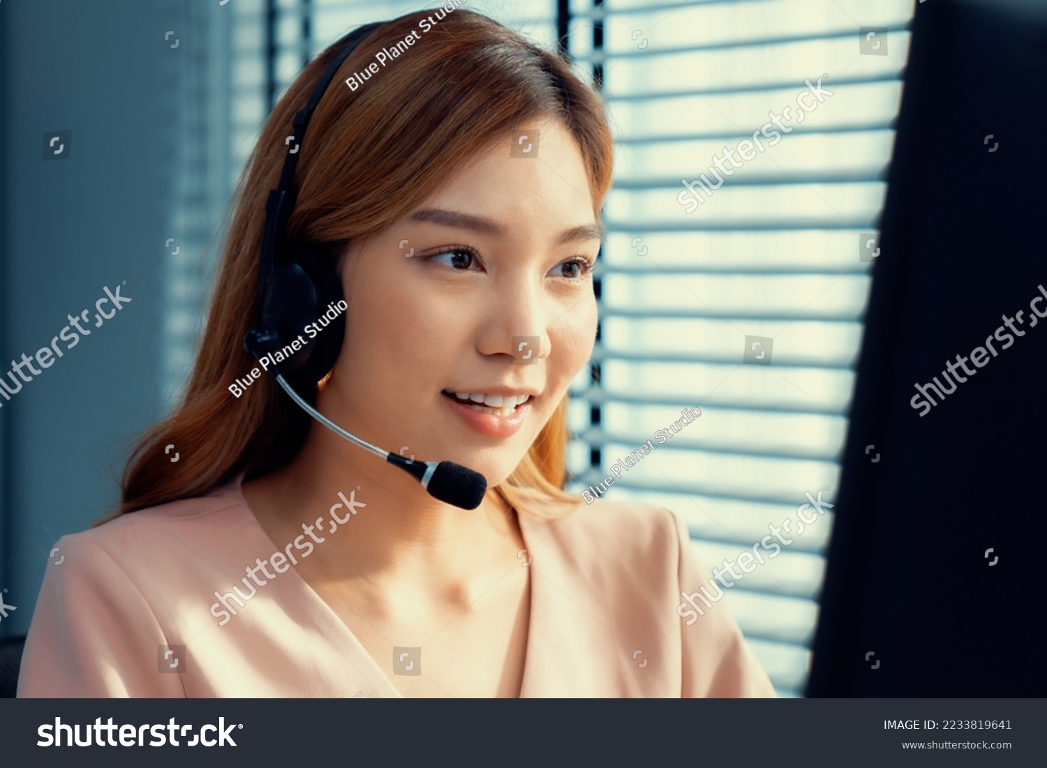 Competent female operator working on computer and while talking with clients. Concept relevant to both call centers and customer service offices. #2233819641