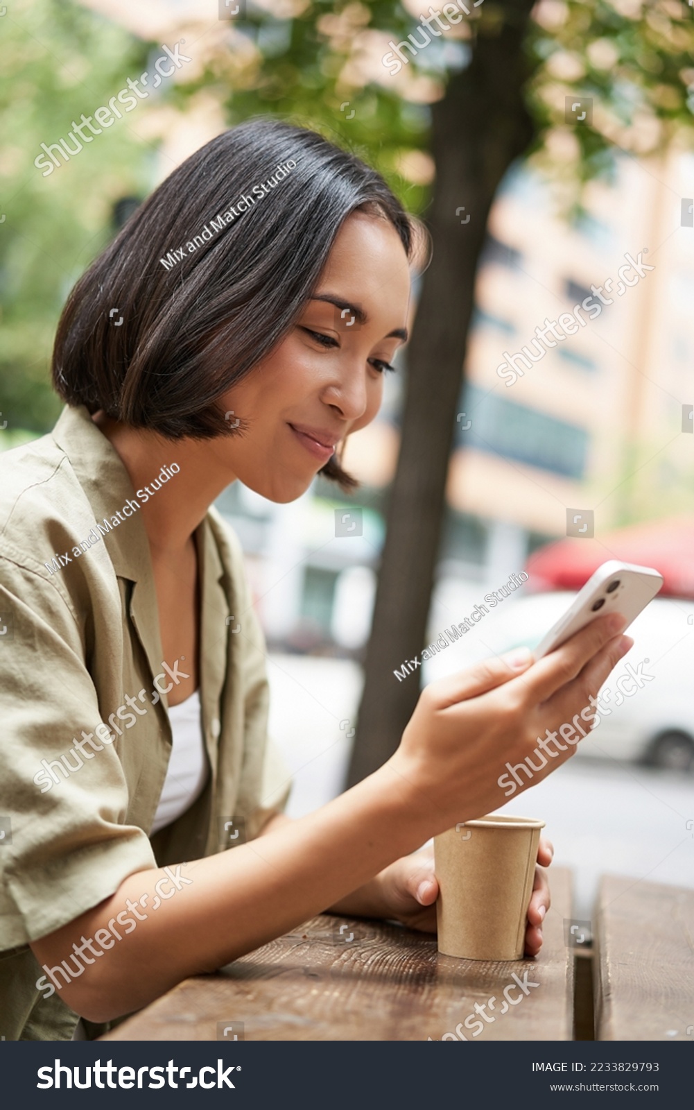 Close up portrait of asian girl sitting in cafe outside, drinking coffee and using smartphone, reading mobile phone. #2233829793