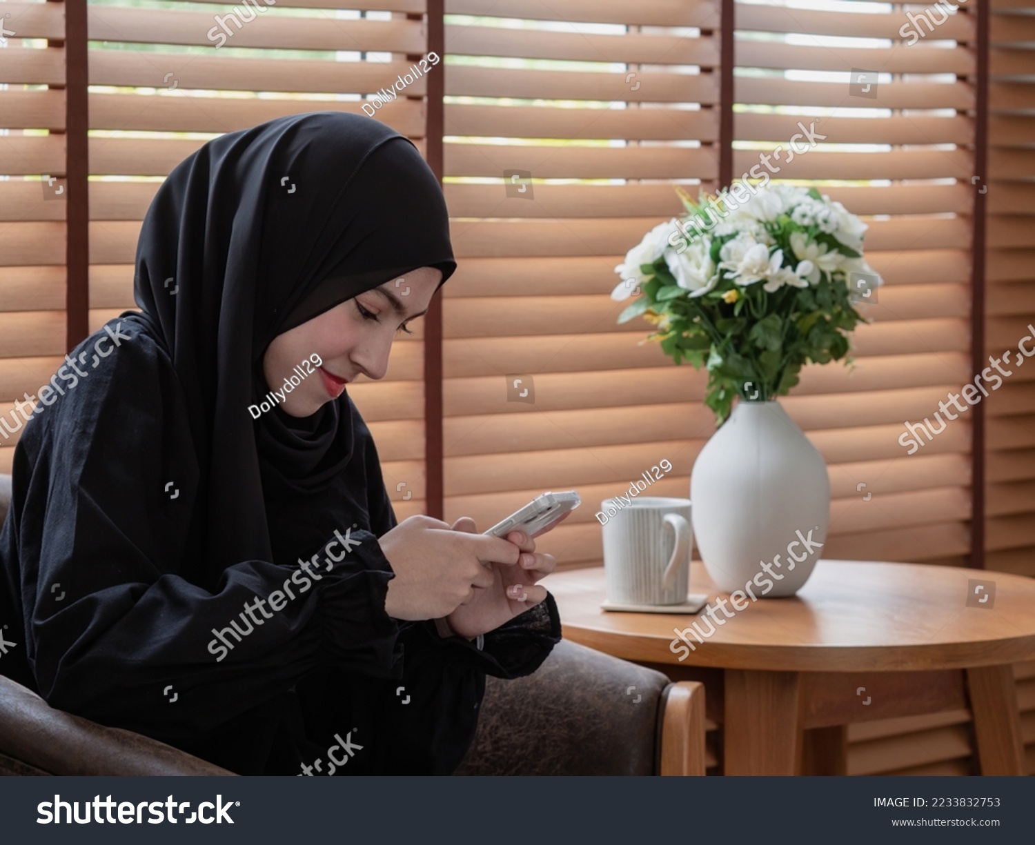 Pretty teenager girl using mobile phone while sitting at coffee table at home. #2233832753