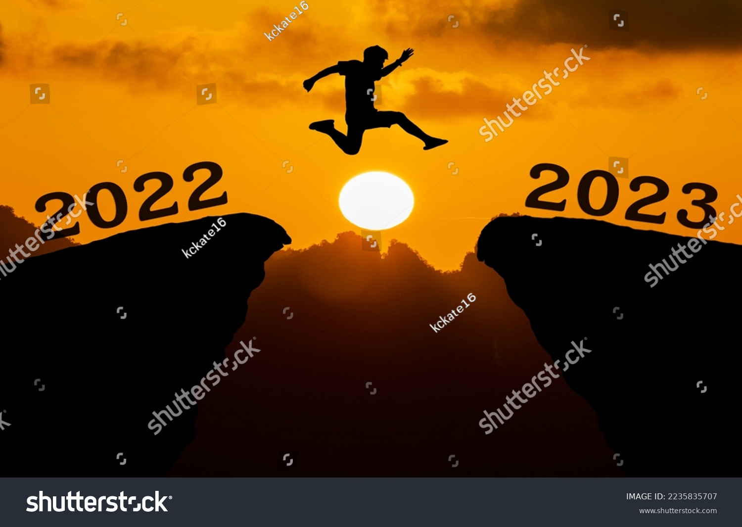 A young man jump between 2022 and 2023 years over the sun and through on the gap of hill silhouette evening colorful sky. happy new year 2023.	 #2235835707