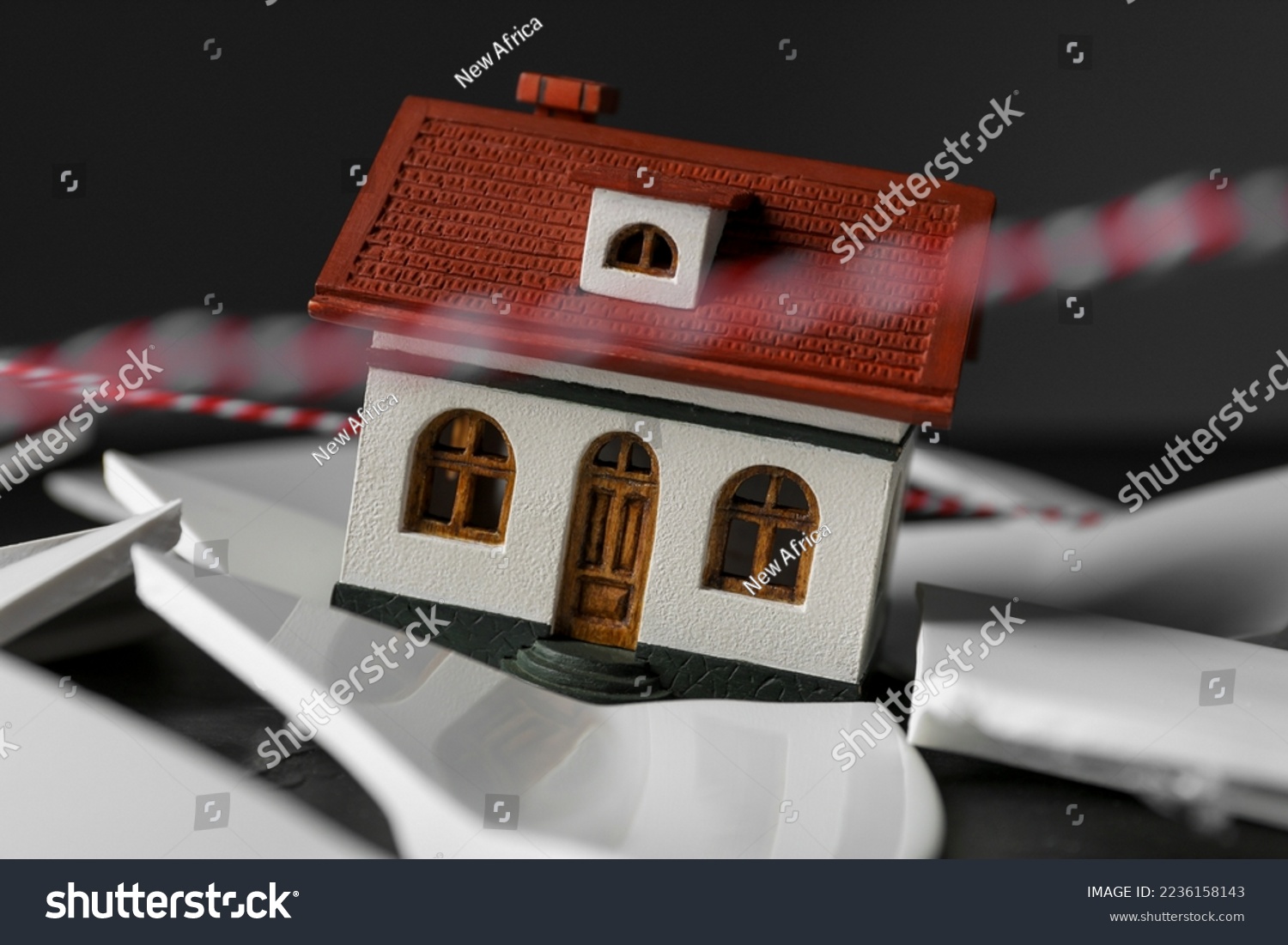 House model and broken dishes on black table depicting destruction after earthquake, closeup #2236158143
