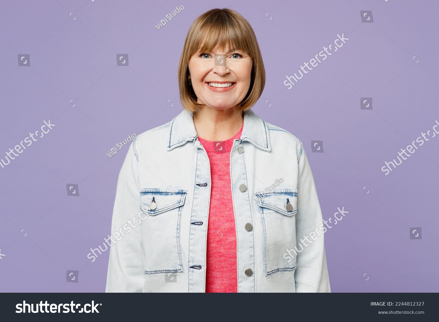 Elderly smiling happy fun cheerful blonde satisfied woman 50s years old she wearing casual clothes denim jacket t-shirt looking camera isolated on plain pastel light purple background studio portrait #2244812327
