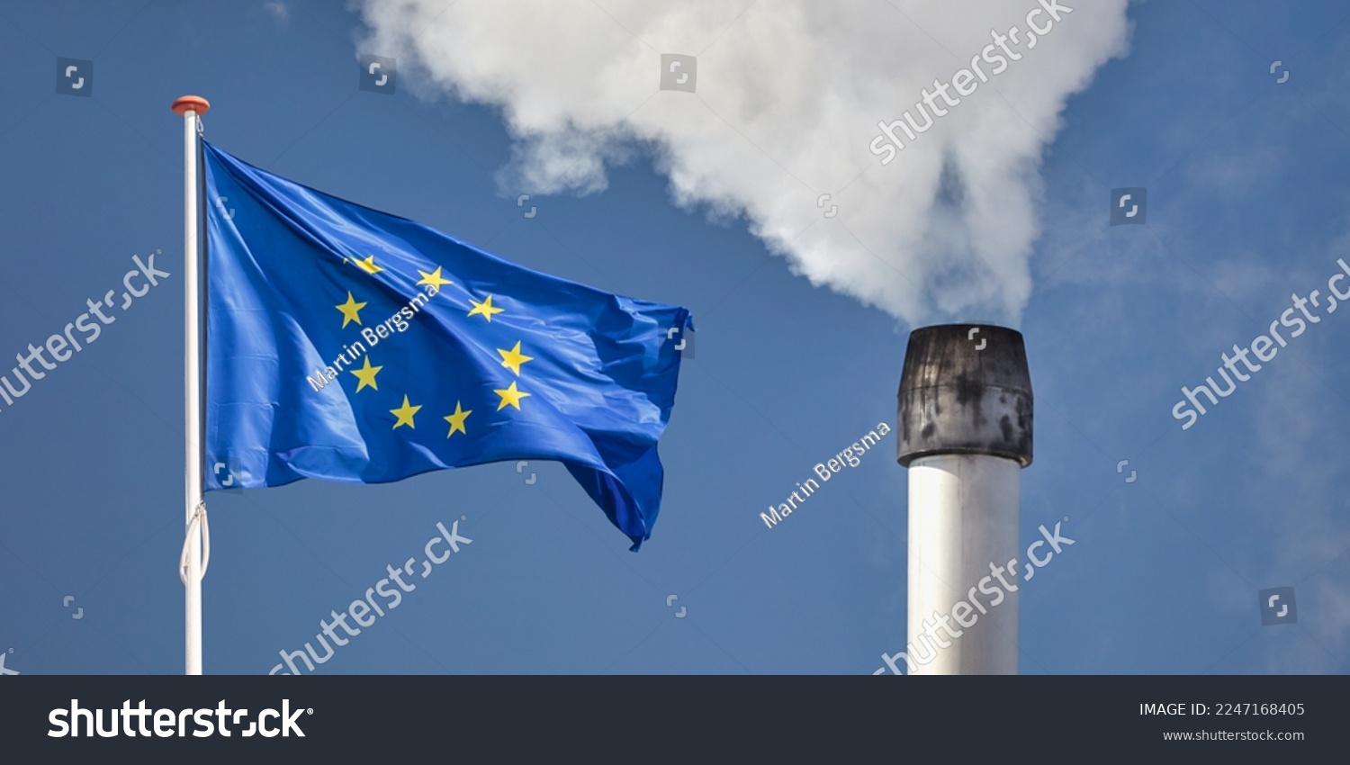 Waving European flag in front of a polluting factory chimney with smoke #2247168405