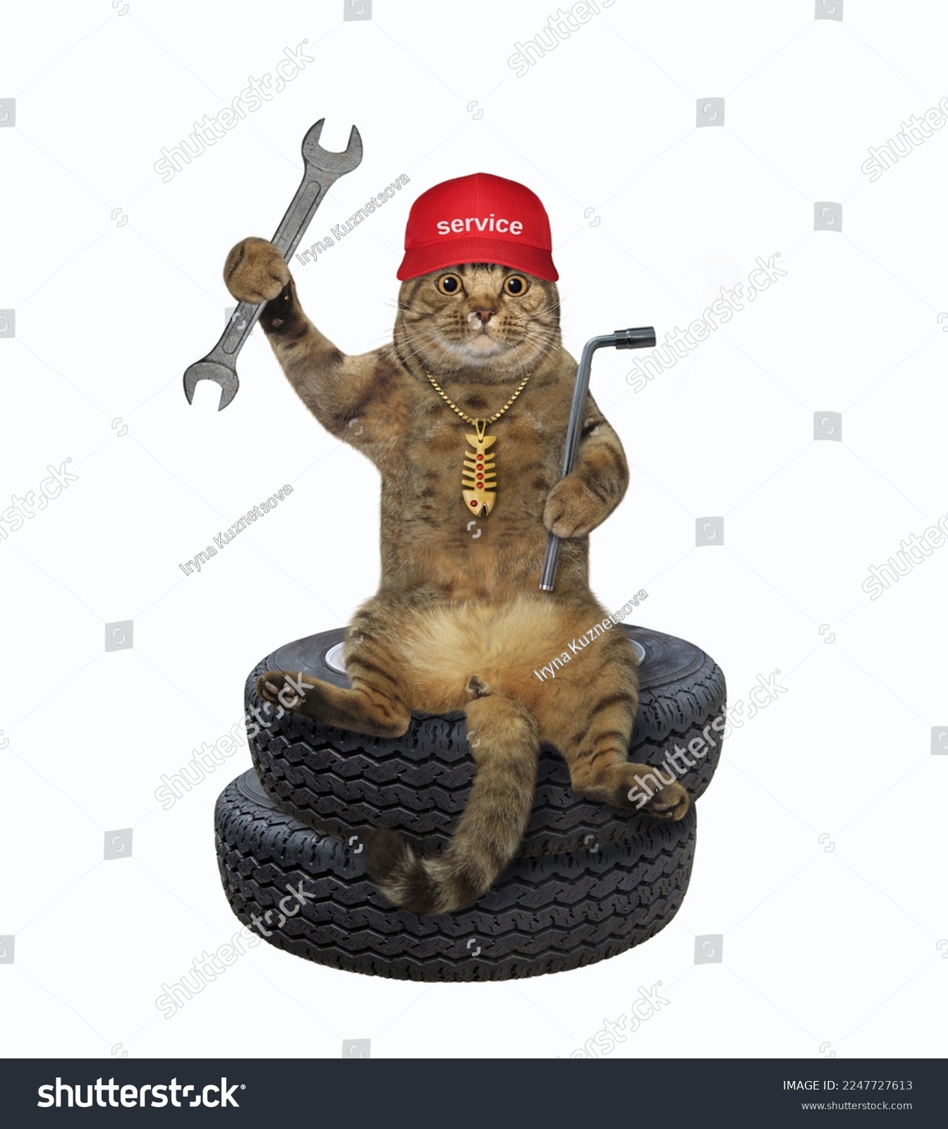A beige cat auto mechanic with car wrenches sits on a stack of tires. White background. Isolated. #2247727613