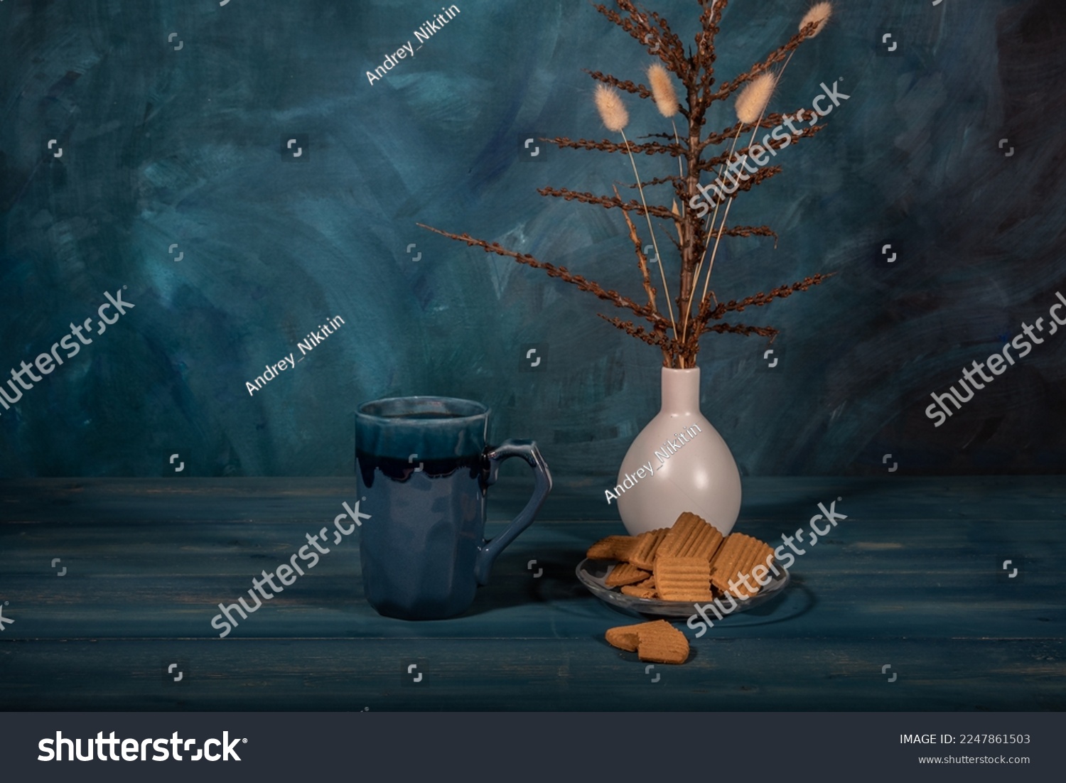 Gingerbread cookies on a saucer, a cup of tea and a bouquet of dry branches in a vase on a dark blue background. #2247861503