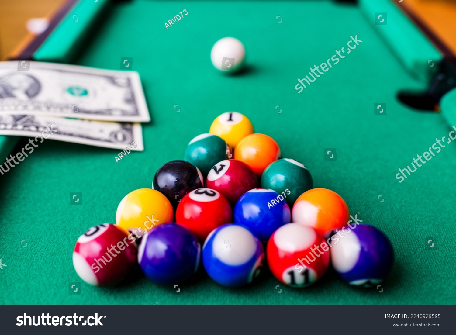 Gambling ardor game.Money and multicolored billiard balls with numbers.Dollar paper banknotes on the game table.Selective focus. #2248929595