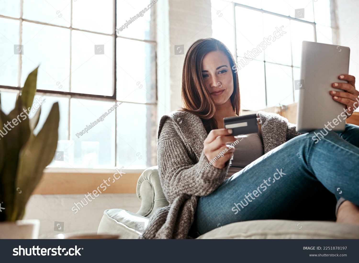 Digital tablet, credit card and woman on a sofa for online shopping, ecommerce and payment while relaxing. Girl, couch and online banking from app, purchase and booking online in a living room #2251878197