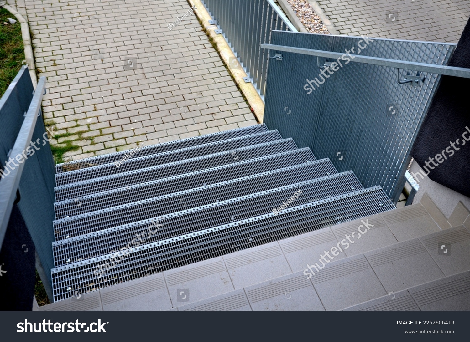 Stairs to a residential building made of stainless steel grid. galvanized stair grating made of expanded metal. lawn concrete sidewalk.  #2252606419