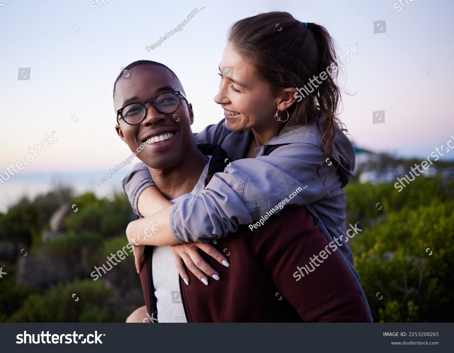 Love, nature and interracial couple piggyback on mountain adventure for holiday, vacation and hiking on weekend. Travel, dating and happy man carry woman enjoying calm, outdoor freedom and peace #2253208265