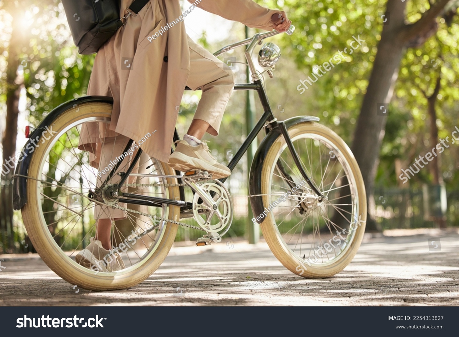 Bicycle, closeup and feet of casual cyclist travel on a bike in a park outdoors in nature for a ride or commuting. Exercise, wellness and lifestyle student cycling as sustainable transport #2254313827