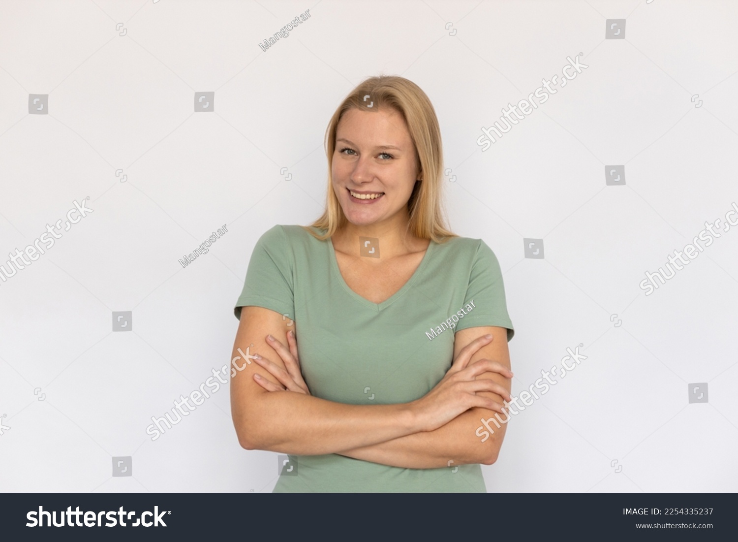 Excited young woman crossing arms. Portrait of happy Caucasian female model with fair hair in green T-shirt looking at camera, smiling, proud of herself. Happiness, success concept #2254335237