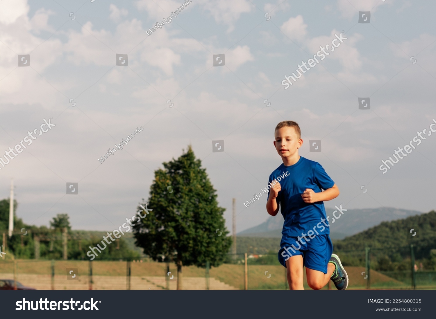Boy running on outdoor track during summer day #2254800315
