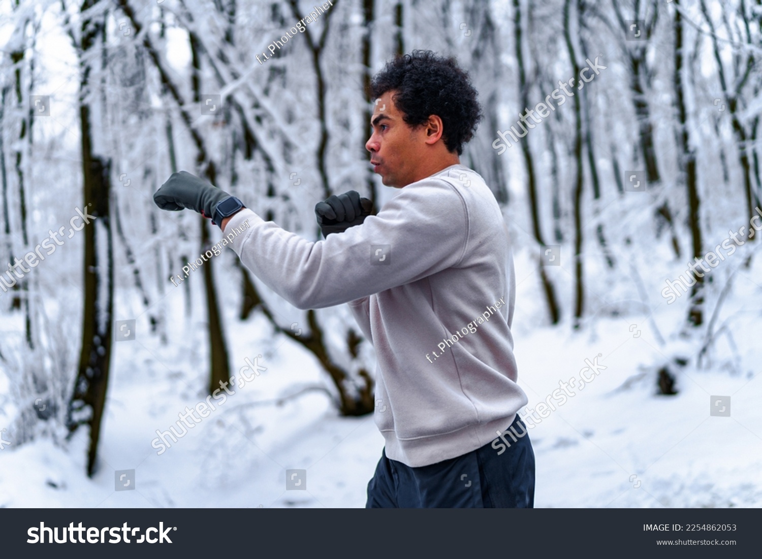 man trains boxing in winter by conducting shadow fight outdoors, in background snow covered forest #2254862053