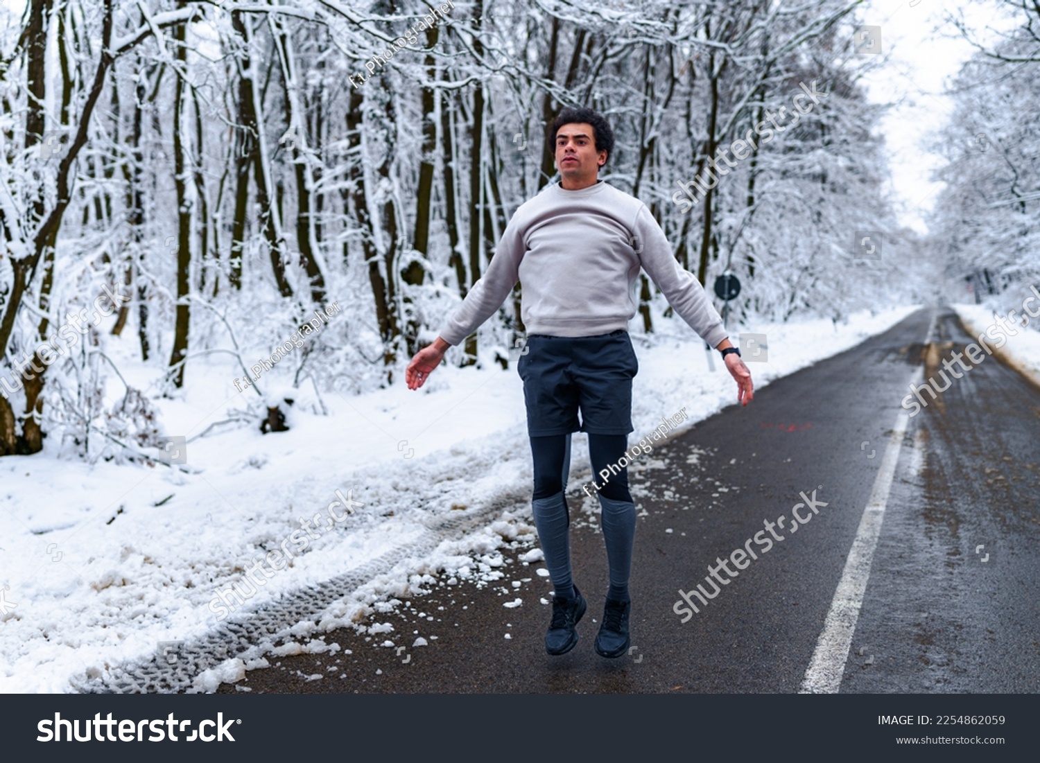 Man doing jumping jacks as a warmup before jogging on a winter day #2254862059