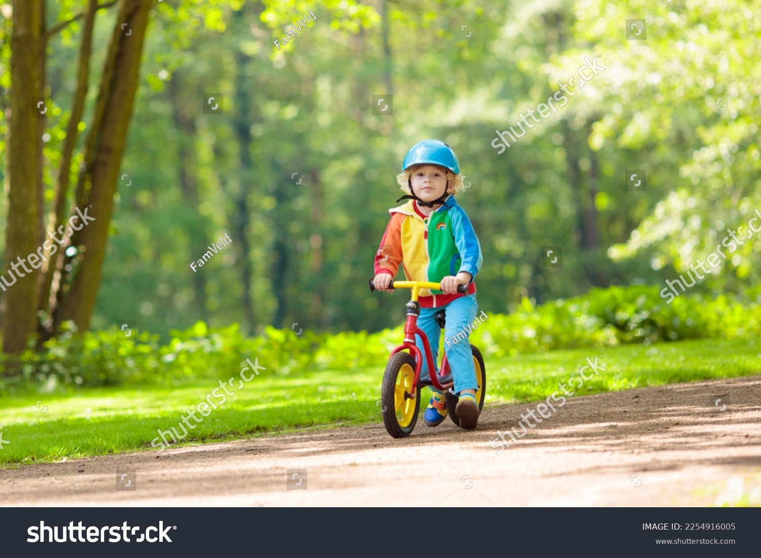 Child riding balance bike. Kids on bicycle in sunny park. Little boy enjoying to ride glider bike on warm summer day. Preschooler learning to balance on run bicycle in safe helmet. Sport for kids. #2254916005
