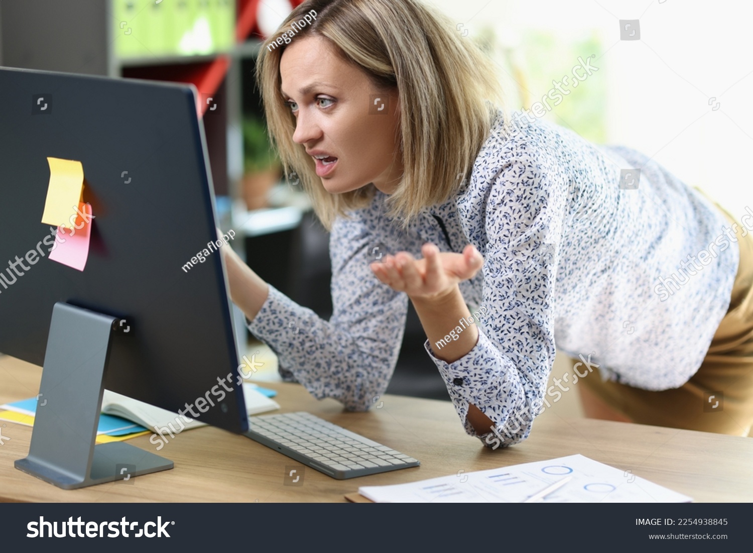 Frustrated business woman looking at computer screen in her office. Unhappy female manager shows upset face while working at computer. #2254938845
