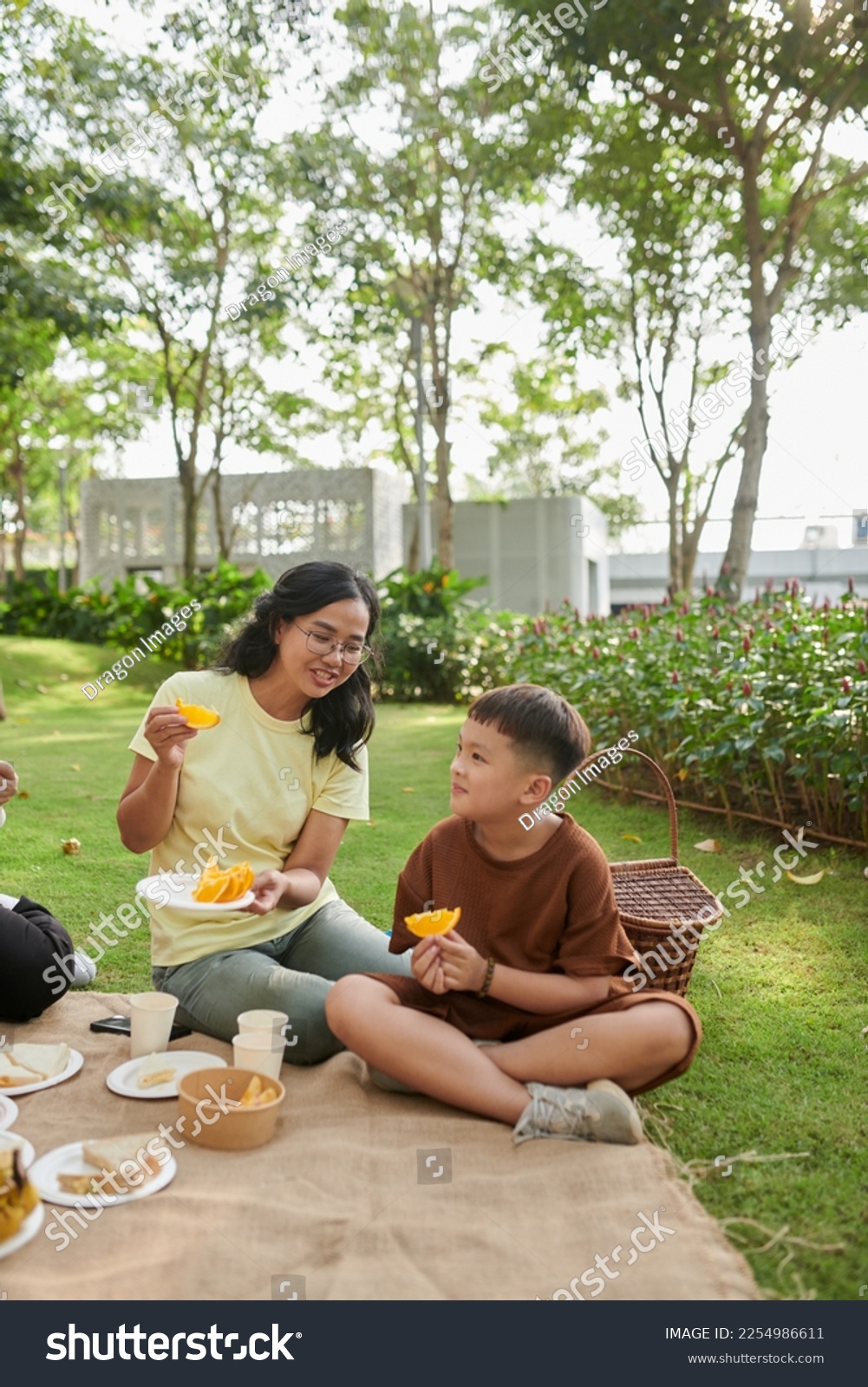 Mother and son eating fresh ripe oranges when enjoying family picnic #2254986611