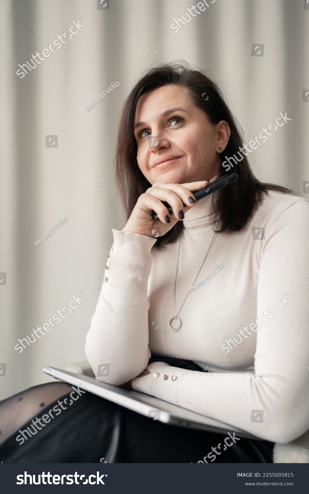 A business woman psychologist smiles using a laptop computer, in beige office clothes. Good mood during the day at work. #2255005815