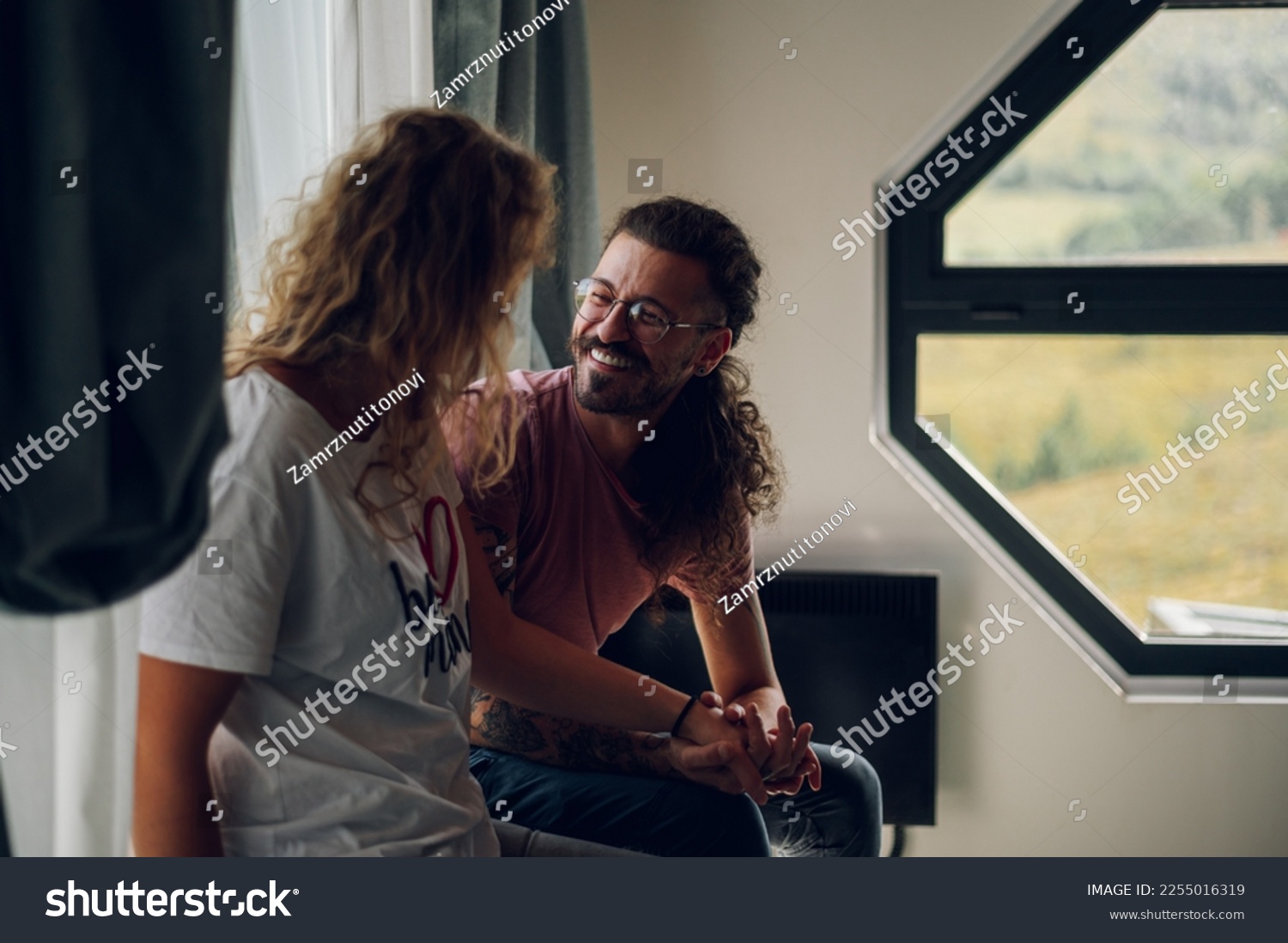 Young couple having fun together at home. Focus on a man holding his girlfriend hands while looking at her and smiling. Adult people relationship and romance. Copy space. #2255016319