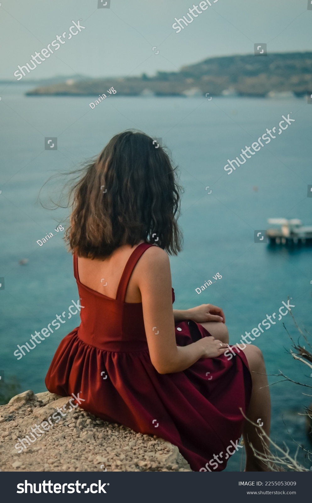
A girl sits over a cliff.Woman on a rock.Resting on the sea.Mediterranean sea.Travel agency.Lady in red.Portrait of a girl at sunrise.Sea tourism and vacation.Woman looks at the sea.Calmness.Pleasure #2255053009