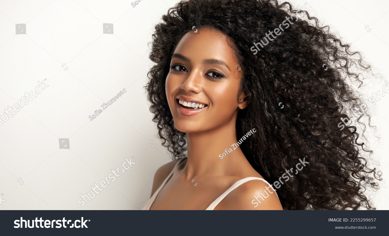 Beauty portrait of african american girl with clean healthy skin on beige background. Smiling dreamy beautiful black woman.Curly  hair in afro style  #2255299657