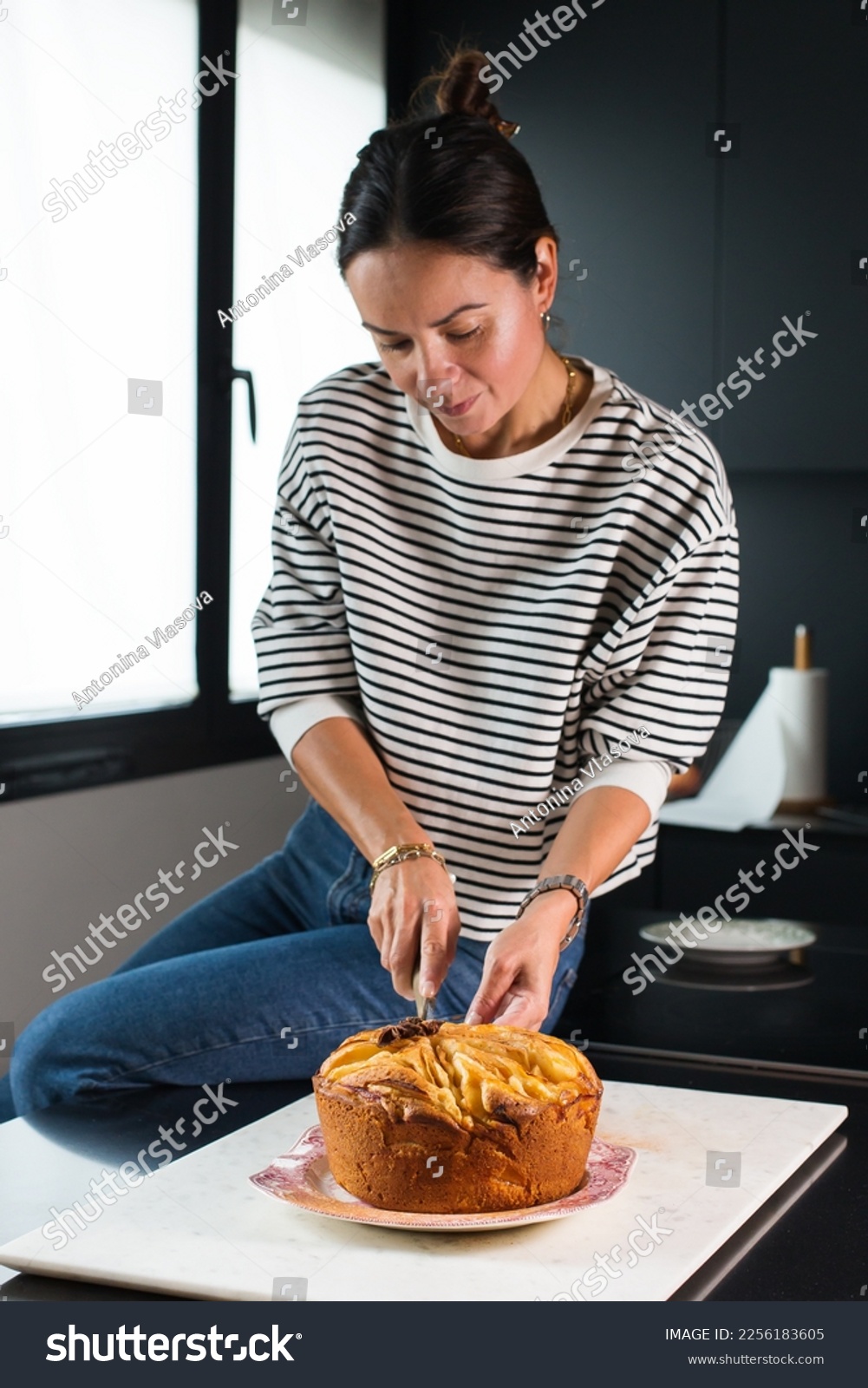 Woman cutting homemade apple pie at the kitchen #2256183605
