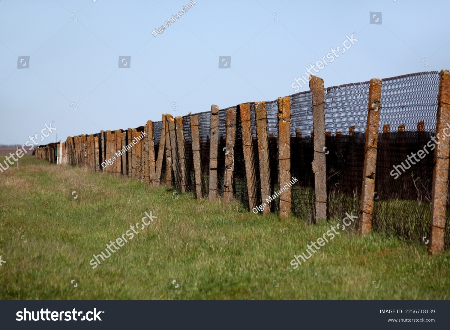 View of animal pen in field against green grass and blue sky #2256718139