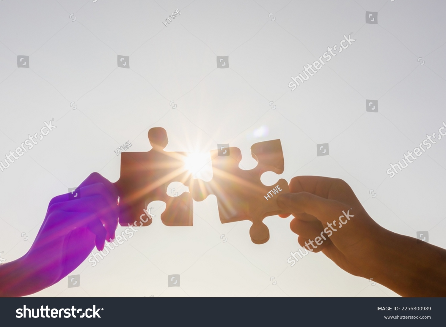 Cooperation Hands holding piece of blank jigsaw puzzle at sunset background #2256800989
