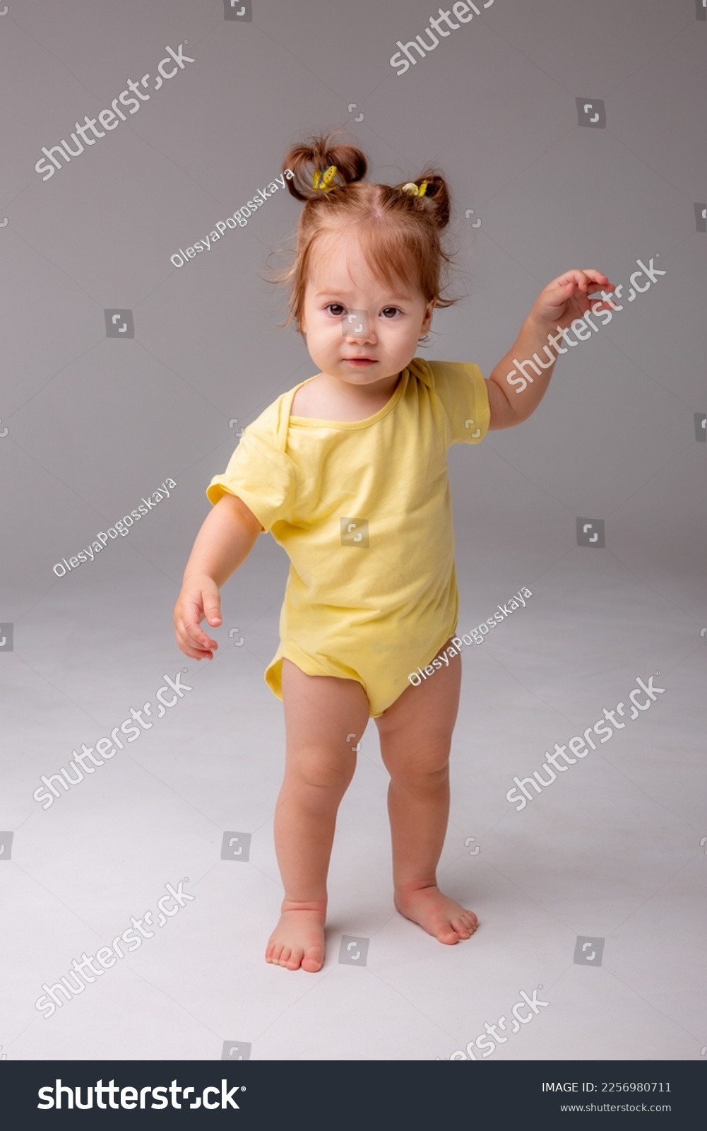 baby girl starting to walk takes her first steps on a white background #2256980711