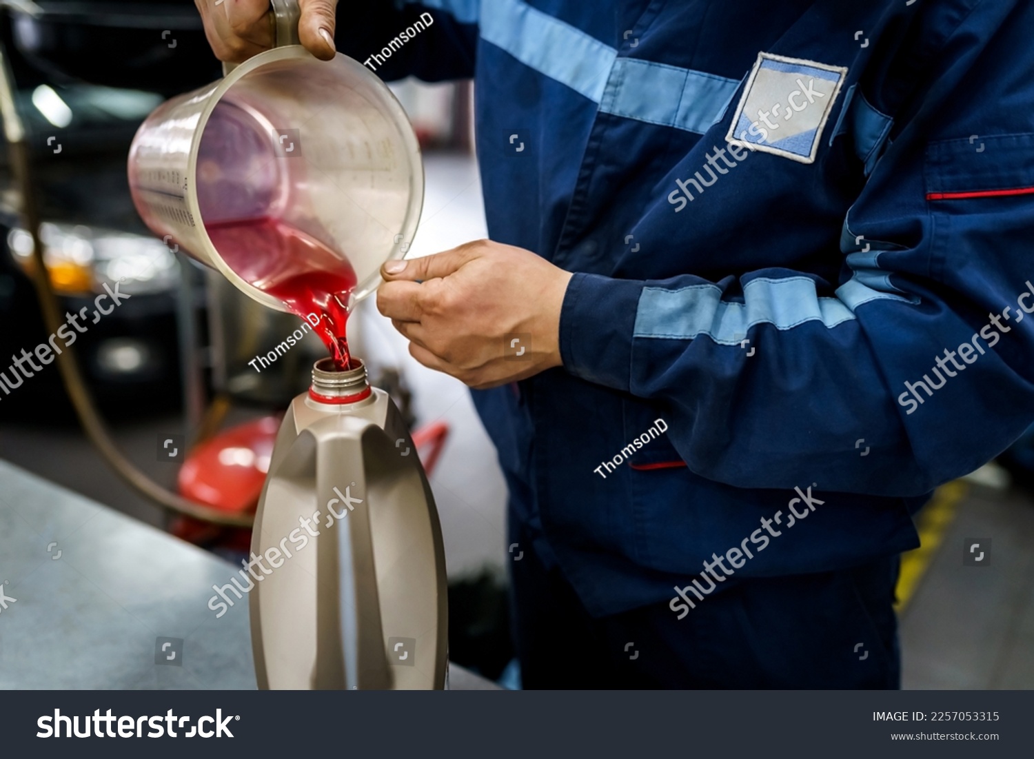 Mechanic pours oil into a canister. Changing the oil in a car engine in a service #2257053315
