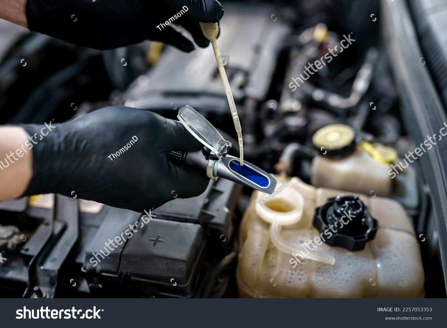 Optical instrument for testing antifreeze, windshield washer fluid and electrolyte density. Mechanic uses car refractometer in service #2257053353