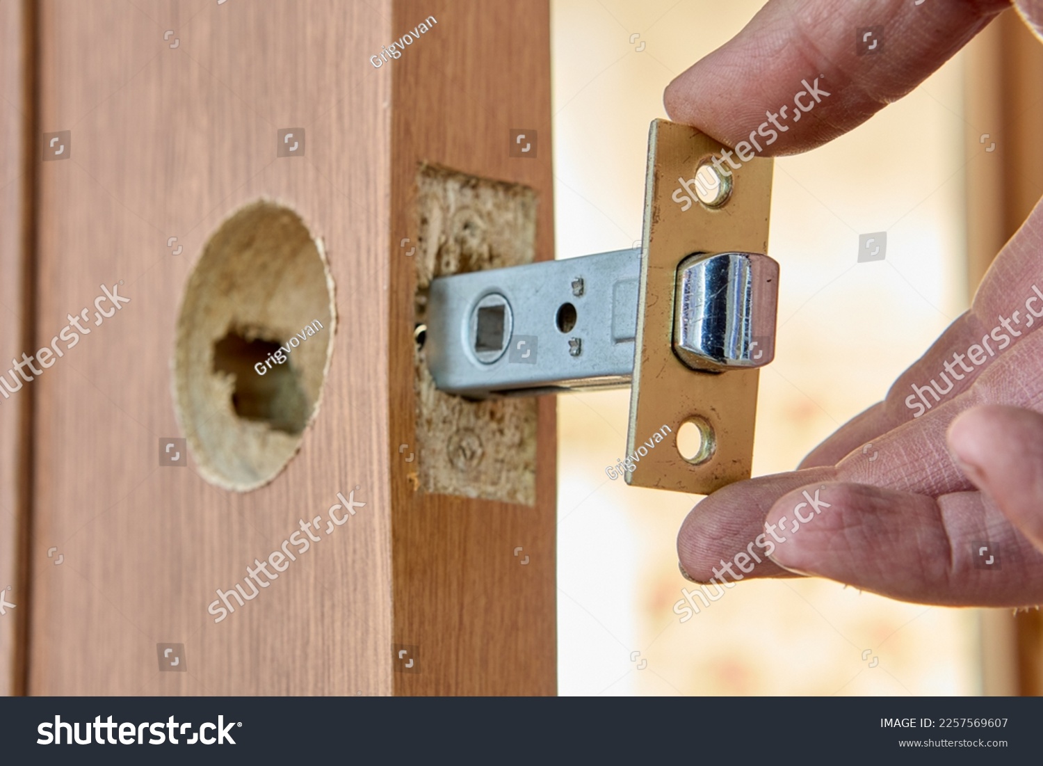 Installing door latch in slot of interior door. #2257569607