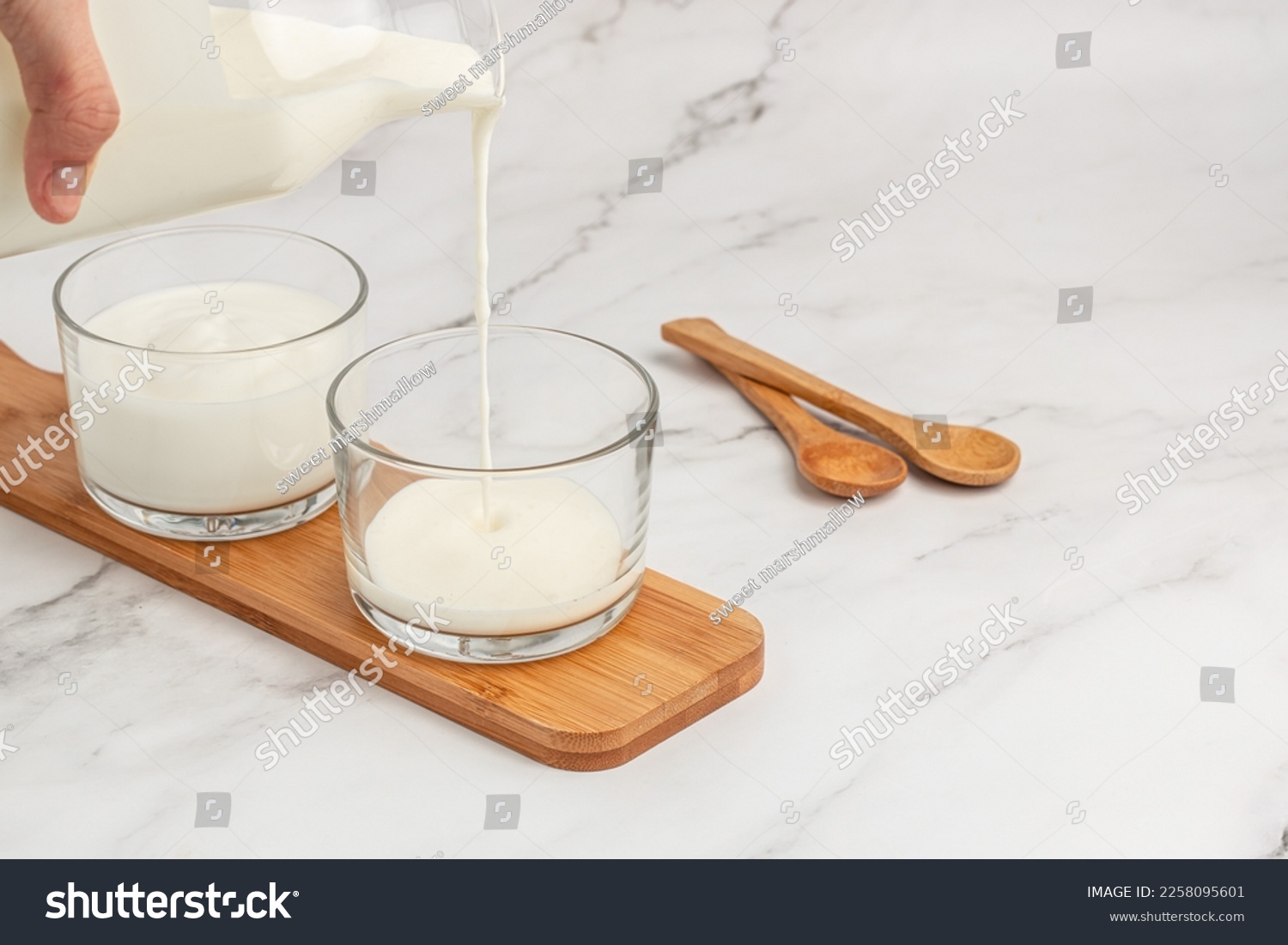 yogurt, kefir, fermented milk pouring into glass. Calcium rich diary product. banner, menu, recipe place for text, top view. #2258095601